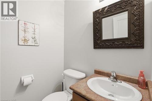 Bathroom featuring a white elongated toilet, a vanity with a drop-in sink, a laminate countertop, and an ornate framed mirror - 84 Duncairn Crescent, Hamilton, ON 