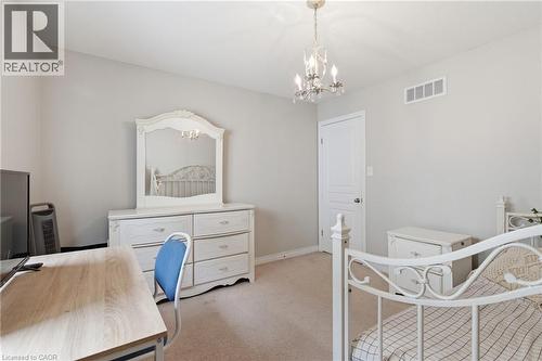 Carpeted room featuring a white door, light grey walls, and a chandelier with crystal accents - 84 Duncairn Crescent, Hamilton, ON 