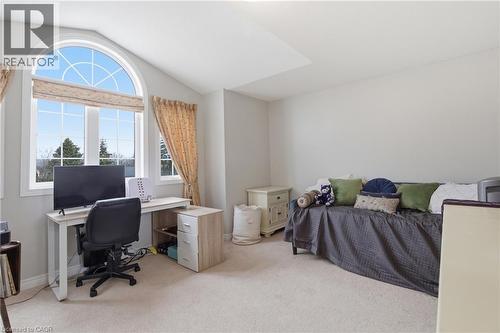 Bright interior room featuring a large arched window, vaulted ceiling, neutral wall paint, and beige carpeting - 84 Duncairn Crescent, Hamilton, ON 