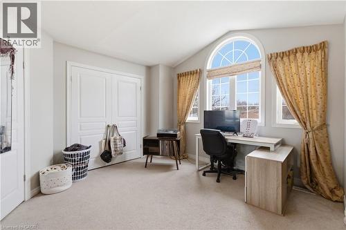 Room featuring an arched window, two additional windows, light-toned carpeting, and double-panel closet doors - 84 Duncairn Crescent, Hamilton, ON 