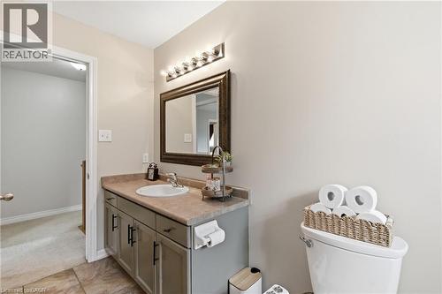 Bathroom vanity featuring a single basin sink, a neutral-toned countertop, and a built-in cabinet with dark hardware - 84 Duncairn Crescent, Hamilton, ON 