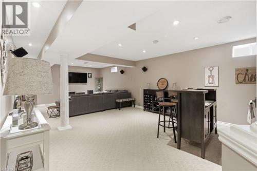 Spacious lower level featuring recessed lighting, carpeted flooring, a built-in bar with storage, and a separate media area - 84 Duncairn Crescent, Hamilton, ON 