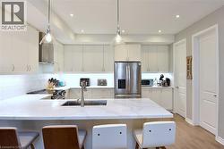 Kitchen featuring a central island with an undermount sink, quartz countertops, and white shaker-style cabinetry - 