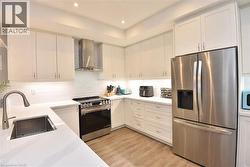 Modern kitchen featuring white cabinetry and wood-finish flooring - 