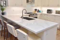 Kitchen featuring an island with a built-in sink, white cabinetry, stainless steel appliances, and subway tile backsplash - 