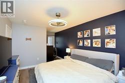 Bedroom featuring wood-finish flooring, a contemporary ceiling light fixture, and a contrasting accent wall - 