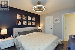 Bedroom featuring a dark accent wall, light gray walls, a contemporary ceiling fan with integrated lighting, and a paneled interior door - 