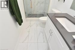 Bathroom featuring a white vanity with a dark countertop, an integrated sink, and brushed nickel hardware - 