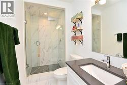 Contemporary bathroom featuring a glass-enclosed shower with large format wall tiles, a rain showerhead, and a mosaic tile floor - 
