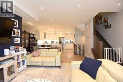 Open-concept living space featuring recessed lighting, light wood-finish flooring, and a kitchen with white cabinetry and stainless steel appliances - 