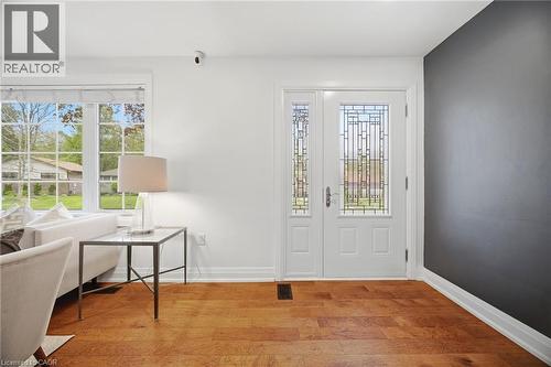 Entryway featuring wood-finish flooring, a white paneled door with decorative glass inserts, and a coordinating sidelight - 1376 Royal Drive, Burlington, ON 
