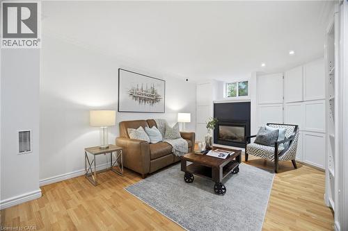 Living area featuring wood-finish flooring, a built-in fireplace with a dark surround, recessed lighting, and extensive built-in white cabinetry - 1376 Royal Drive, Burlington, ON 