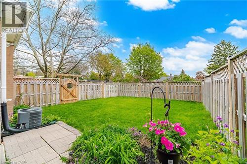 Private backyard featuring a well-maintained lawn, perimeter fencing with lattice details, and a distinctive wooden gate - 1376 Royal Drive, Burlington, ON 