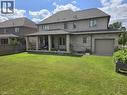 Expansive backyard featuring a large green lawn, covered patio with stone pillars, and a built-in garden bed - 2719 Torrey Pines Way, London, ON 