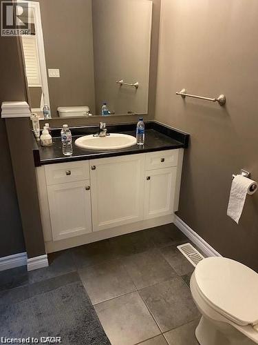 Bathroom vanity featuring a white cabinet with brushed nickel hardware, an integrated sink, and a dark countertop - 4 Isaiah Drive, Kitchener, ON 