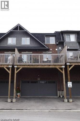 Multi-level townhome featuring brick and shingle siding, a prominent gabled roofline, and a private wooden deck - 4 Isaiah Drive, Kitchener, ON 