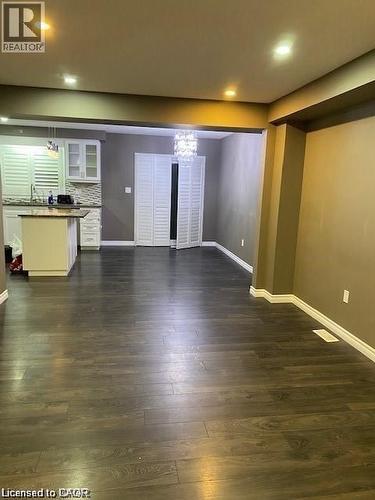 Open-concept living space with dark wood-finish flooring, recessed ceiling lighting, and a contemporary chandelier - 4 Isaiah Drive, Kitchener, ON 