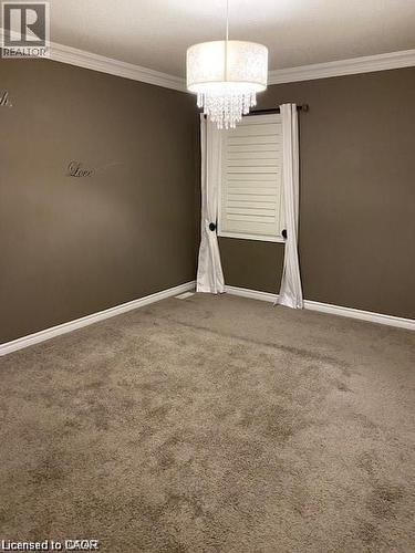 Room featuring wall-to-wall carpeting, crown molding, and a drum shade chandelier with crystal accents - 4 Isaiah Drive, Kitchener, ON 