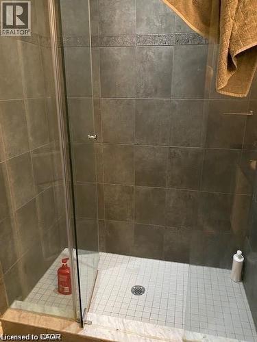 Walk-in shower featuring glass enclosure, large format wall tiles with decorative accent band, and mosaic tile shower pan - 4 Isaiah Drive, Kitchener, ON 