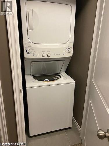 Dedicated laundry closet featuring a white stacked washer and dryer unit, top-loading washer, and tiled flooring - 4 Isaiah Drive, Kitchener, ON 