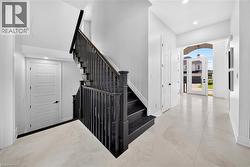 Foyer with a dark wood staircase and light-toned tile flooring - 