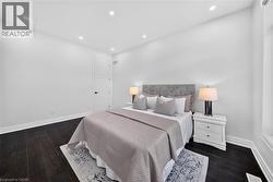 Spacious room featuring dark wood-finish flooring, recessed ceiling lighting, and a five-panel interior door with matte black hardware - 