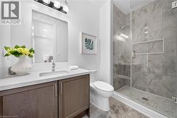 Bathroom featuring a glass-enclosed shower with large format grey wall tiles and a built-in niche - 