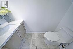 Bathroom featuring a built-in vanity with a speckled countertop, undermount sink, and light wood-finish cabinetry - 