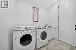 Laundry room featuring a single window, built-in cabinetry, an integrated sink, and gray-toned floor tiling - 