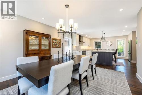 Open-concept dining area featuring dark wood-finish flooring and a contemporary chandelier - 23 Mackenzie Drive, Georgetown, ON 