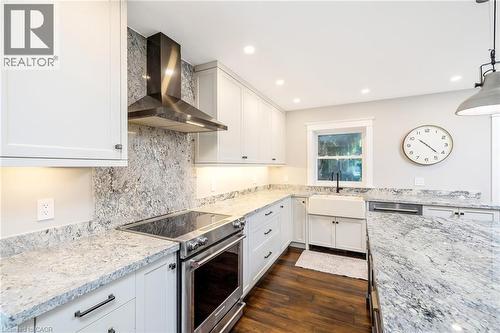 Kitchen featuring white shaker cabinetry, stainless steel appliances, speckled stone countertops, and dark wood-finish flooring - 23 Mackenzie Drive, Georgetown, ON 