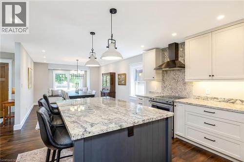 Kitchen featuring an expansive island with a patterned countertop, beadboard paneling, and pendant lighting - 23 Mackenzie Drive, Georgetown, ON 