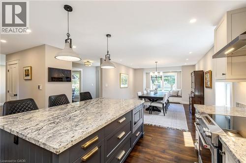 Open-concept kitchen and dining area featuring a spacious island with a stone countertop and pendant lighting - 23 Mackenzie Drive, Georgetown, ON 