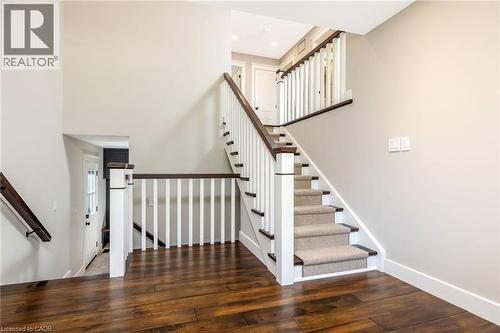 Hardwood-finish flooring grounding a staircase with carpeted treads, white balusters, and dark wood handrails - 23 Mackenzie Drive, Georgetown, ON 