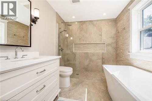 Bathroom featuring a frameless glass shower enclosure, a standalone soaking tub, and a white vanity with an integrated sink - 23 Mackenzie Drive, Georgetown, ON 