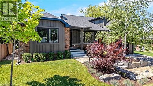Modern exterior featuring dark wood-look vertical siding, brick accents, and a dark shingle roof - 23 Mackenzie Drive, Georgetown, ON 