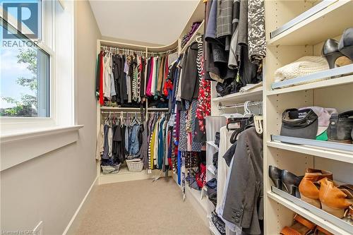 Walk-in closet featuring extensive built-in shelving, multiple hanging rods, pull-out shoe racks, and plush carpet flooring - 23 Mackenzie Drive, Georgetown, ON 