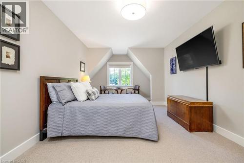 Carpeted room featuring a window with natural light, a mounted flat-screen television, sloped ceilings, and white trim - 23 Mackenzie Drive, Georgetown, ON 