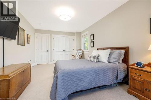 Carpeted room featuring a ceiling-mounted light fixture, a window with white trim, and two paneled doors - 23 Mackenzie Drive, Georgetown, ON 