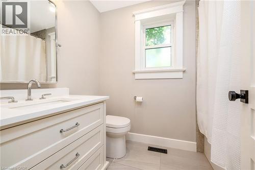 Bathroom featuring a white vanity with an integrated sink, polished chrome fixtures, and a framed mirror - 23 Mackenzie Drive, Georgetown, ON 