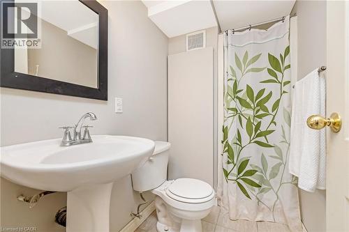 Bathroom featuring a pedestal sink with chrome faucet, a toilet, and a shower area with a curtain rod - 23 Mackenzie Drive, Georgetown, ON 