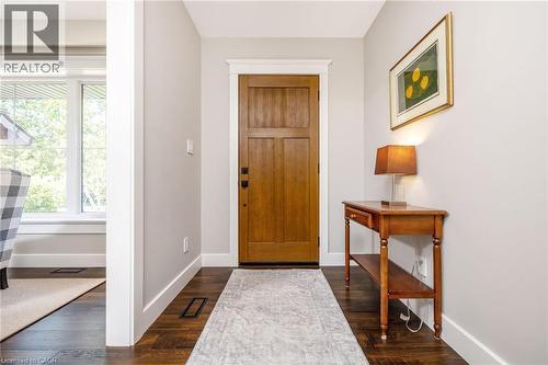 Rich wood-finish flooring complements the solid wood entry door, framed by clean white trim - 23 Mackenzie Drive, Georgetown, ON 