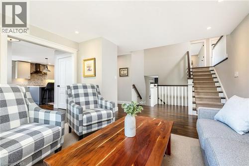Living area featuring rich wood-finish flooring, recessed lighting, and a staircase with carpeted treads and white risers - 23 Mackenzie Drive, Georgetown, ON 