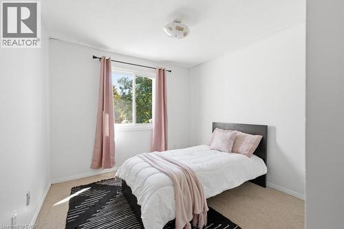Bedroom featuring a window with natural light, neutral wall colors, textured carpeting, and a ceiling-mounted light fixture - 14 Gateway Drive, Guelph, ON 