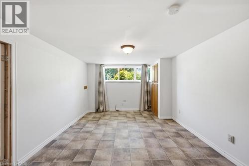 Spacious room featuring neutral-toned tile flooring, white walls, and a window providing natural light - 14 Gateway Drive, Guelph, ON 