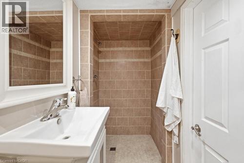 Bathroom featuring a tiled shower stall with a mosaic floor, a white vanity with an integrated sink, a chrome faucet, and a framed wall mirror - 14 Gateway Drive, Guelph, ON 