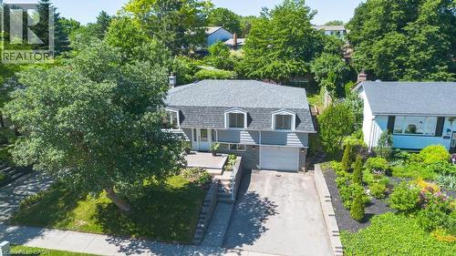 Dormer-style residence featuring a gray facade, integrated garage, and a long concrete driveway - 14 Gateway Drive, Guelph, ON 