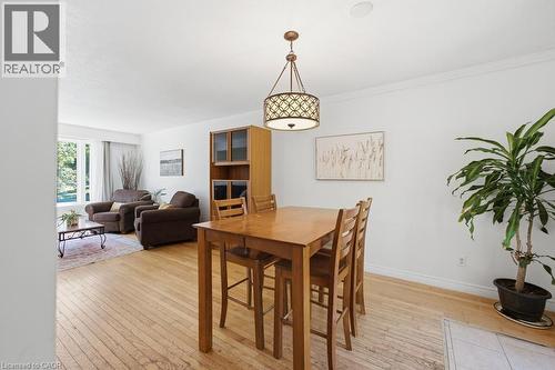 Hardwood flooring in a dining area featuring a geometric drum chandelier and a built-in display cabinet - 14 Gateway Drive, Guelph, ON 