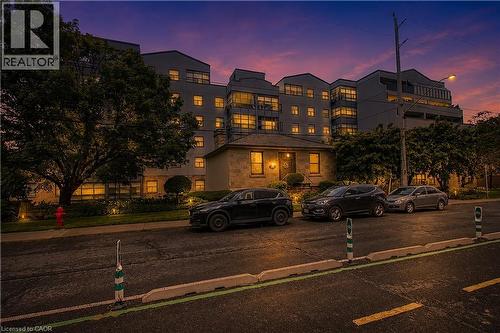 Multi-story building featuring multiple balconies, numerous windows, and exterior lighting - 175 Hunter Street E Unit# 401, Hamilton, ON - Outdoor