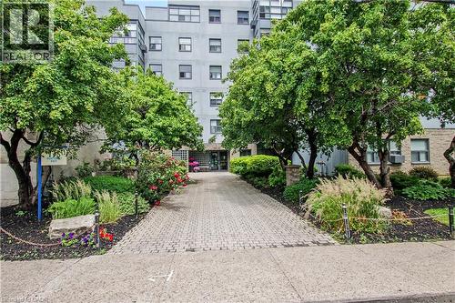 Paved driveway entrance with mature trees and landscaped garden beds - 175 Hunter Street E Unit# 401, Hamilton, ON - Outdoor